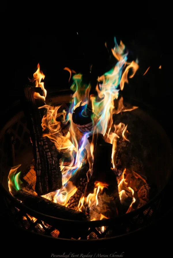 Firelight Ritual Gallery Image | Meriem Chrrouhi Gold and blue-green flames rising from logs in a dark metal fire basket.