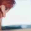 Quiet Personal Reflection — Video Preview | Personalized Tarot Reading Close-up side profile of a red-haired woman looking downward in soft daylight.
